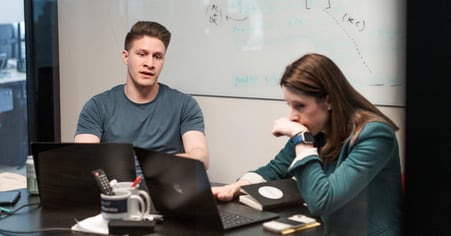 Two Pioneer employees sitting at a desk, working, and talking