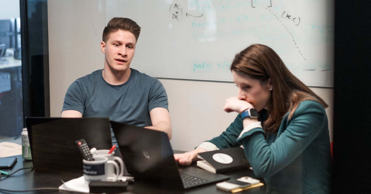 Two Pioneer employees sitting at a desk, working, and talking