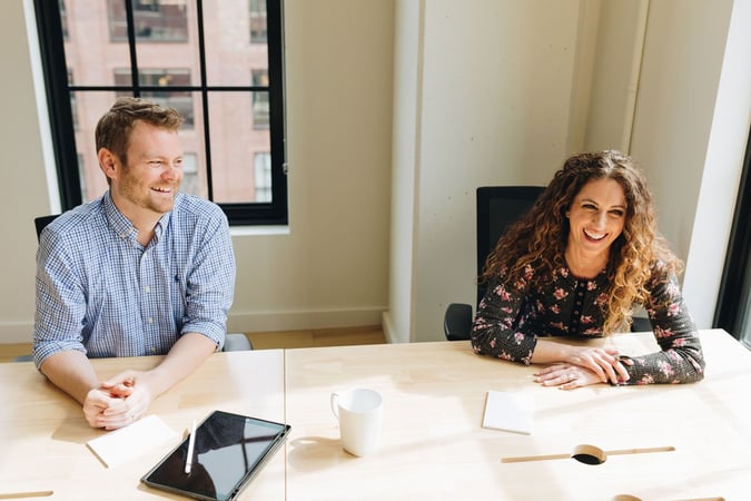 A man and a woman sitting at a conference table.