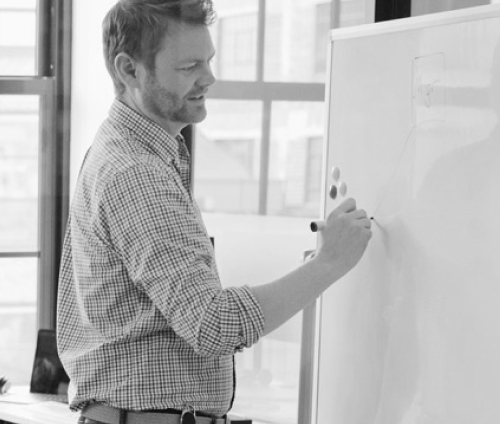 A man writing on a white board.