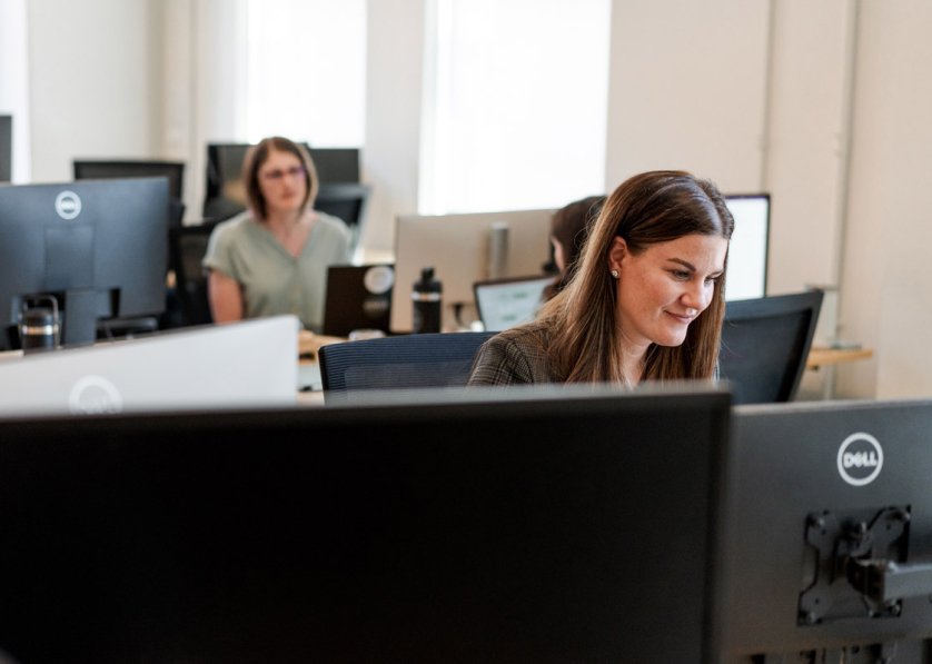 Two women sitting at desks looking at their computers.