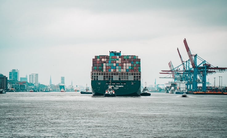 A large cargo ship in a harbor with a city in the background.