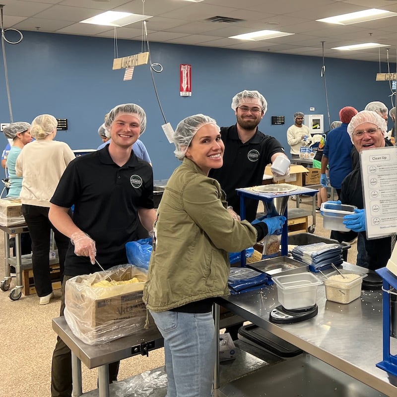 People wearing hairnets filling bags with food.