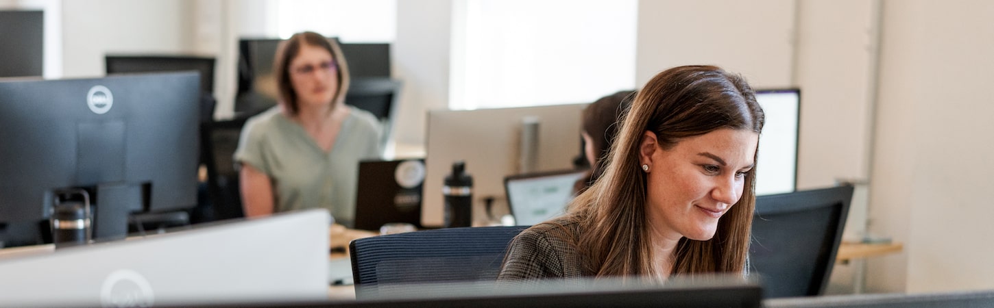 Two women sitting at computer desks.