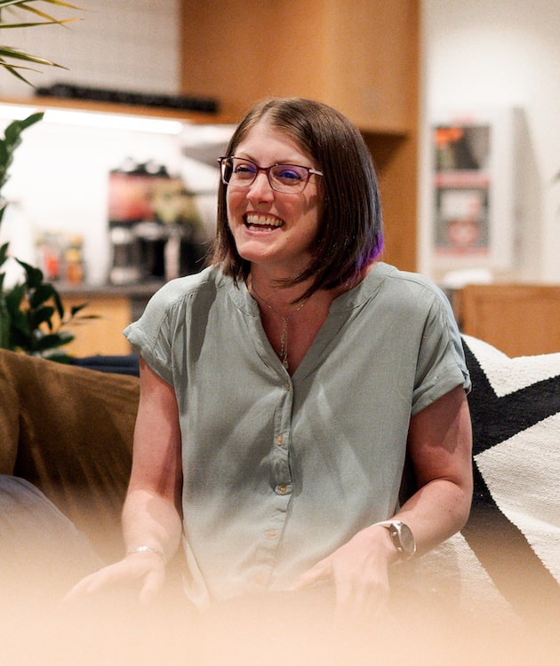 Woman sitting on couch laughing.